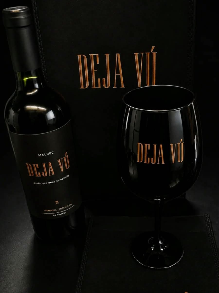 Copa negra grabada Deja V&uacute; junto a la botella