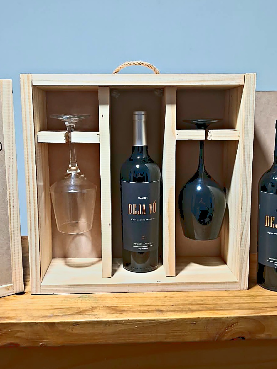 Estuche de madera abierto con un Malbec Deja V&uacute; en el medio y dos copas colgadas a los costados
